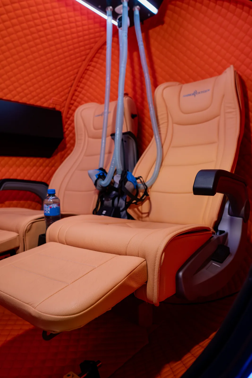 Seats and breathing equipment inside the orange-padded Amber Oxygen chamber