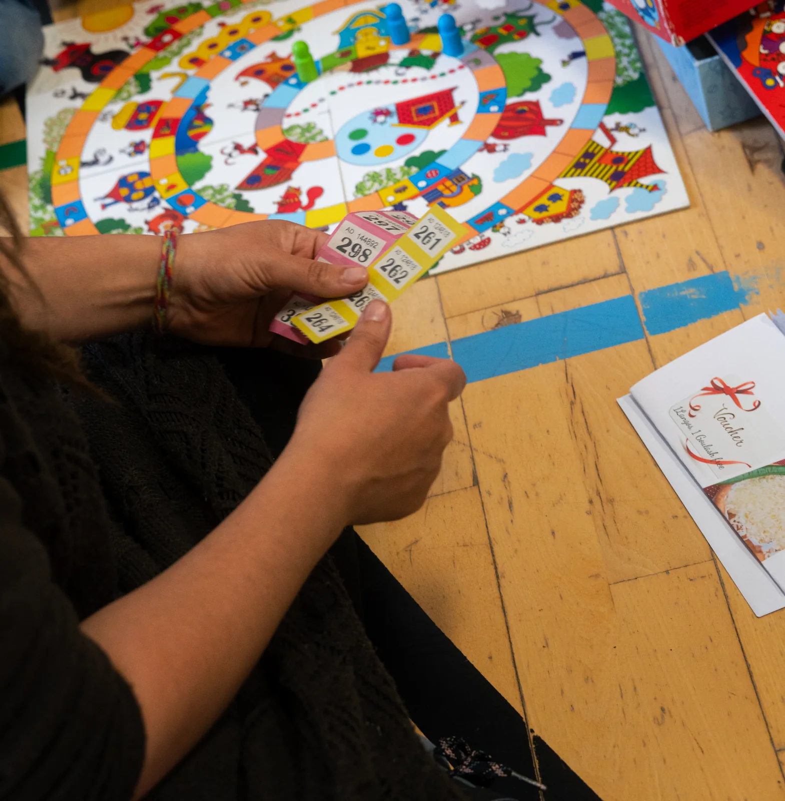 Hands and numbered tickets beside a colourful board game
