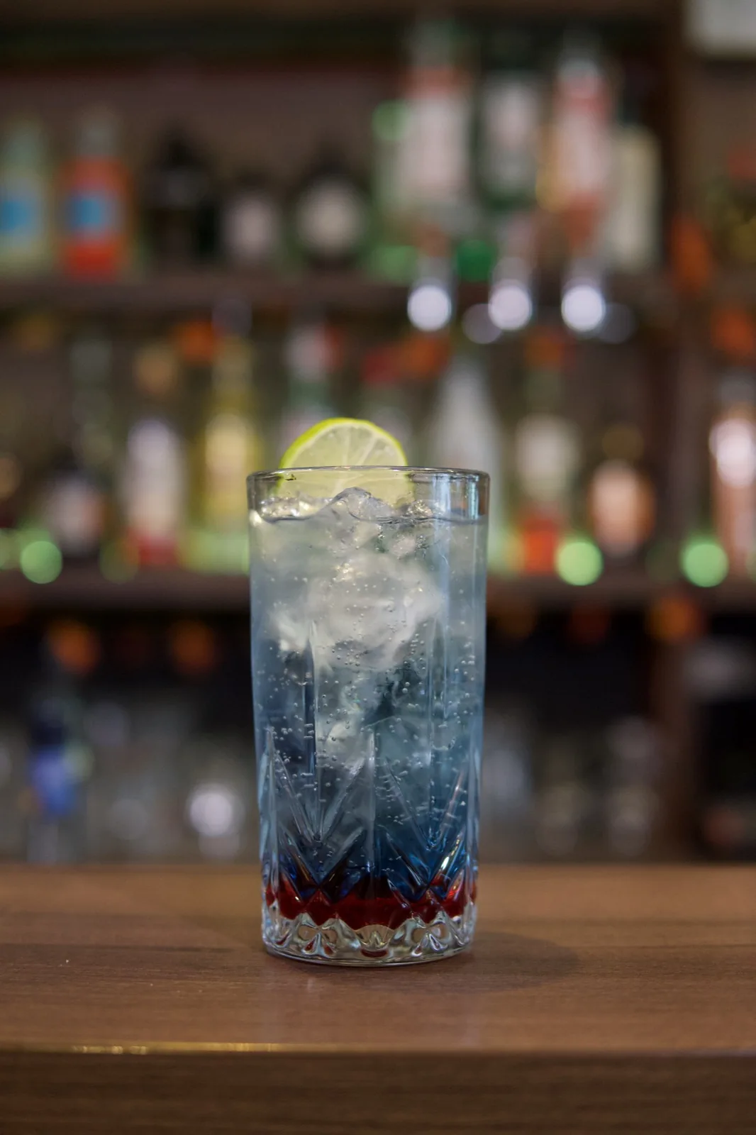 A tall drink with ice and citrus photographed against the Úri Muri bar background